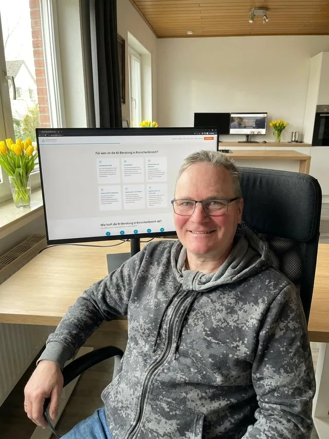 KI-Berater Sven Frank aus Korschenbroich am Schreibtisch mit KI-Beratungs-Website im Hintergrund
